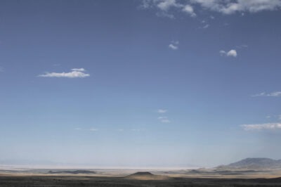 the Nevada desert, flat plains, small mountains, mostly sky, a few scattered clouds