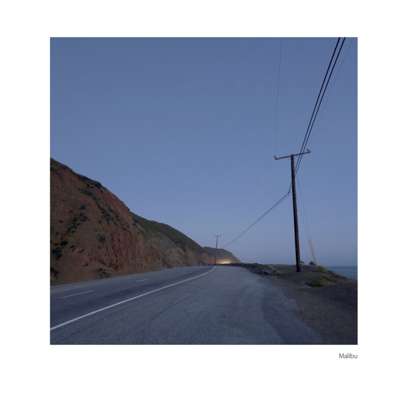 highway 1 at the west end of Malibu, along the cliffs, the ocean, headlights in the distance, just after sunset